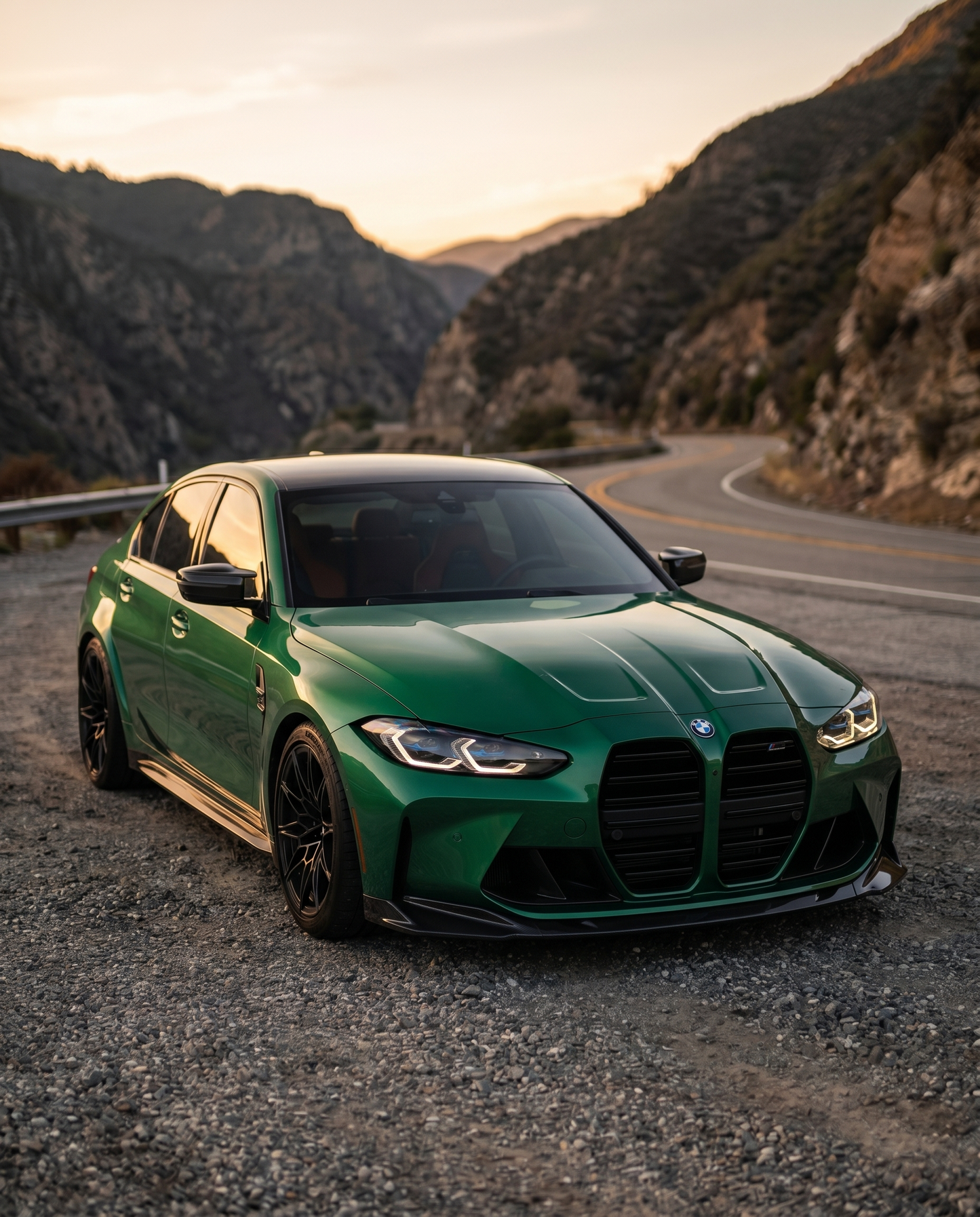BMW G80 M3 Competition with gloss carbon front lip at canyon dusk, low golden-hour raking light, aggressive lowered motorsport stance
