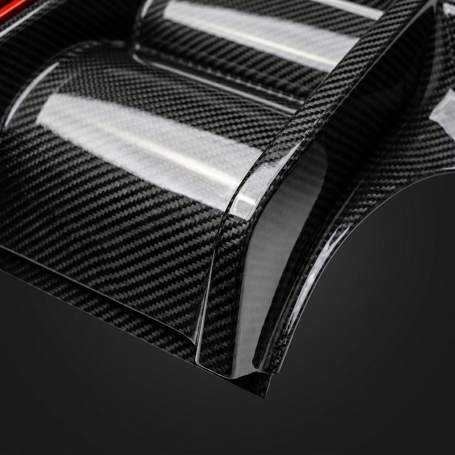 Macro of gloss 2x2 twill carbon weave over BMW M3 V4 diffuser fin, clean light-bar reflection and machined edge detail