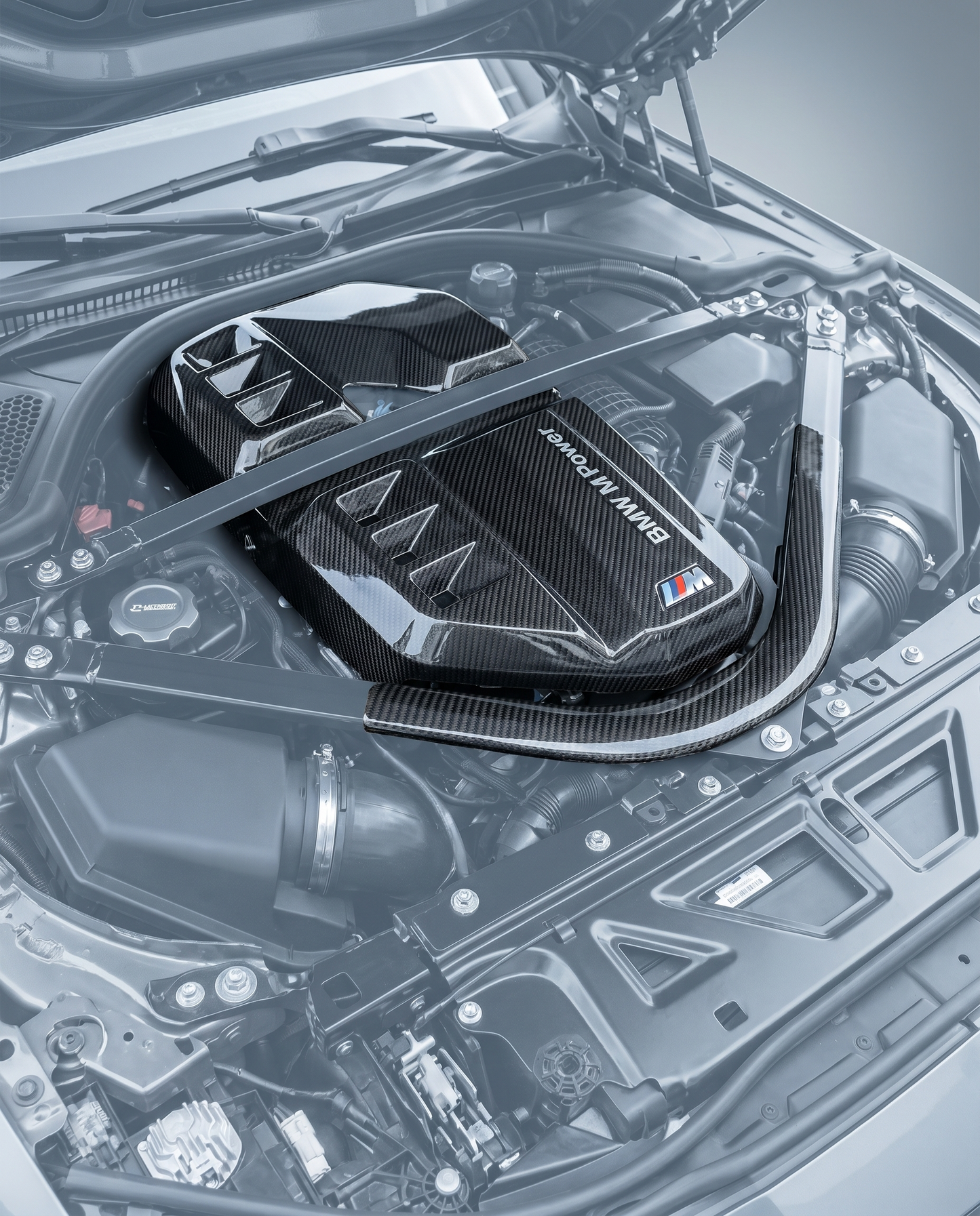 Dry carbon air intake cover installed in ghosted BMW G80 M3 S58 engine bay, race-inspired carbon focal point, OEM bolt-on fit