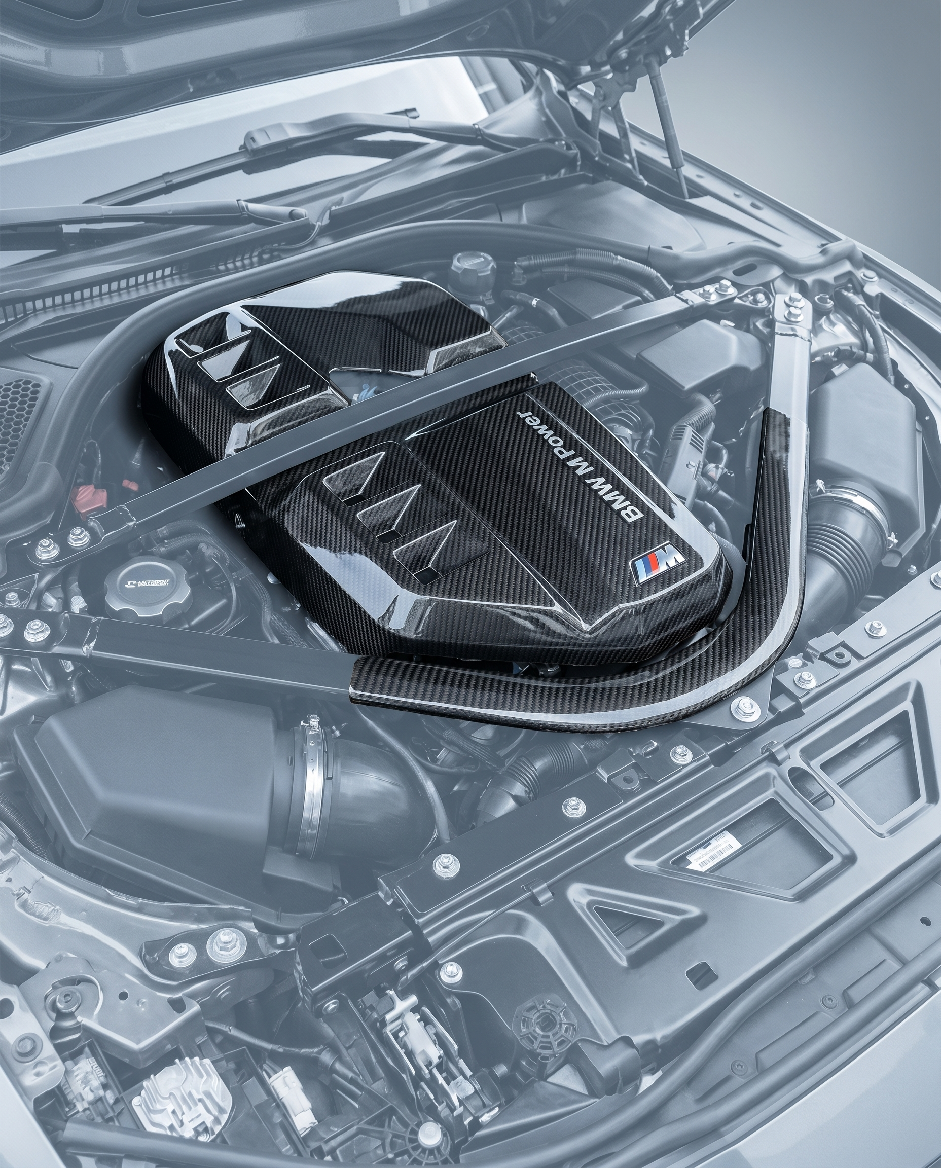 Dry carbon air intake cover installed in ghosted BMW G80 M3 S58 engine bay, race-inspired carbon focal point, OEM bolt-on fit