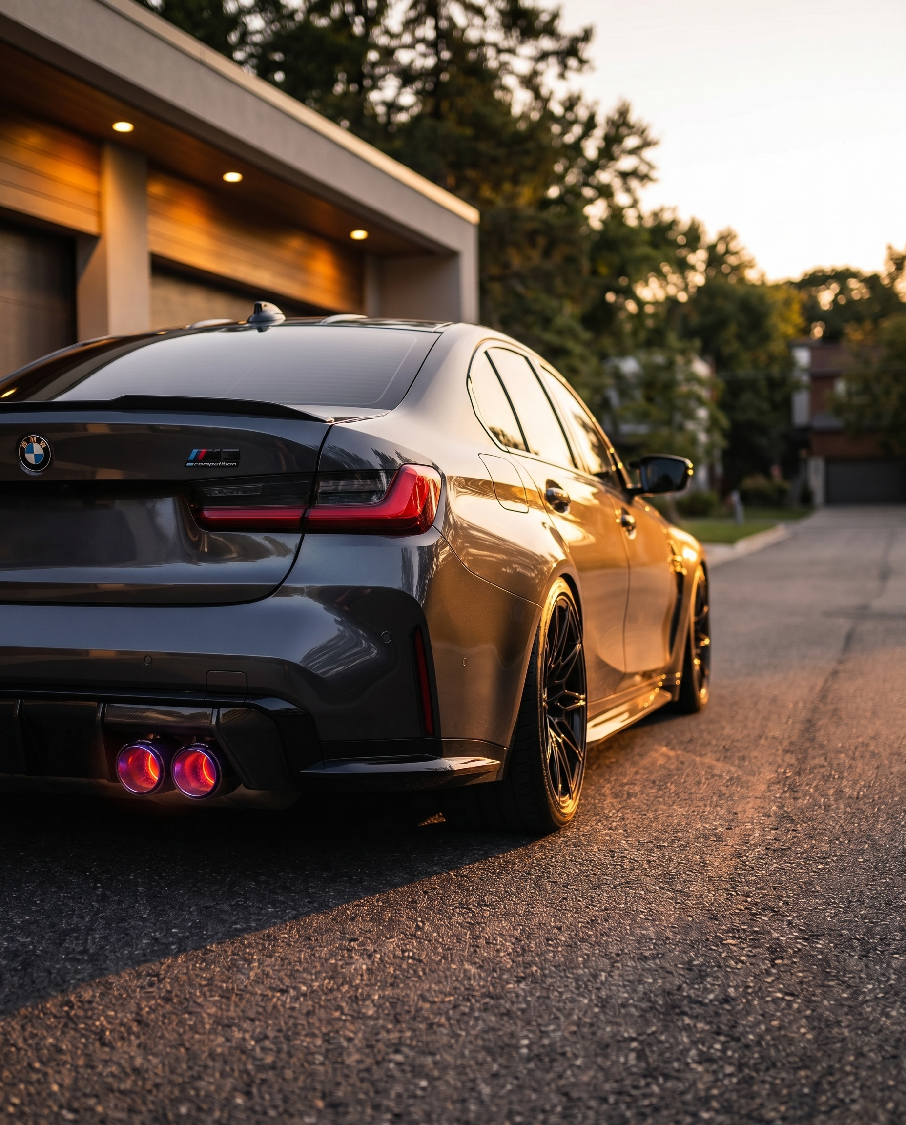 BMW G80 M3 rear at dusk with flat-cut burnt titanium carbon exhaust tips catching warm light, aggressive lowered motorsport stance