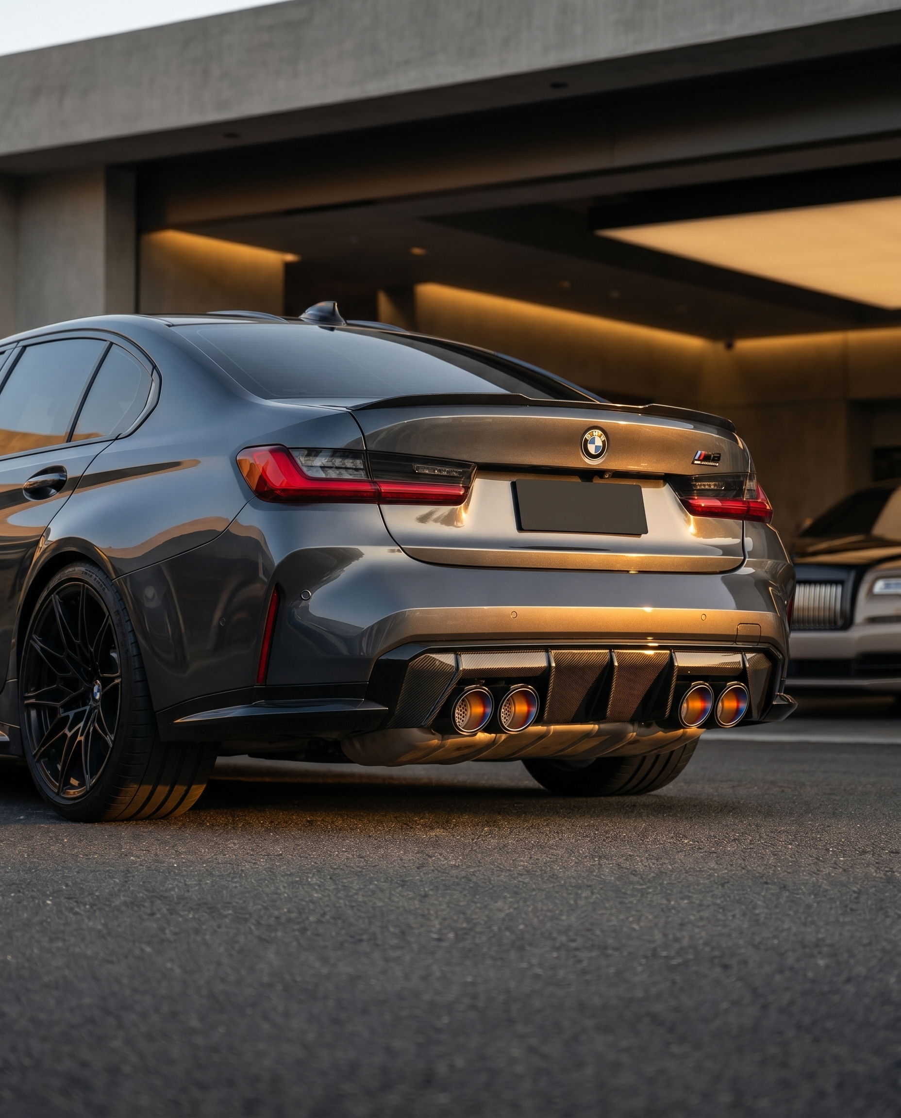 BMW G80 M3 rear at dusk with angle-cut burnt titanium carbon exhaust tips catching warm light, aggressive lowered motorsport stance