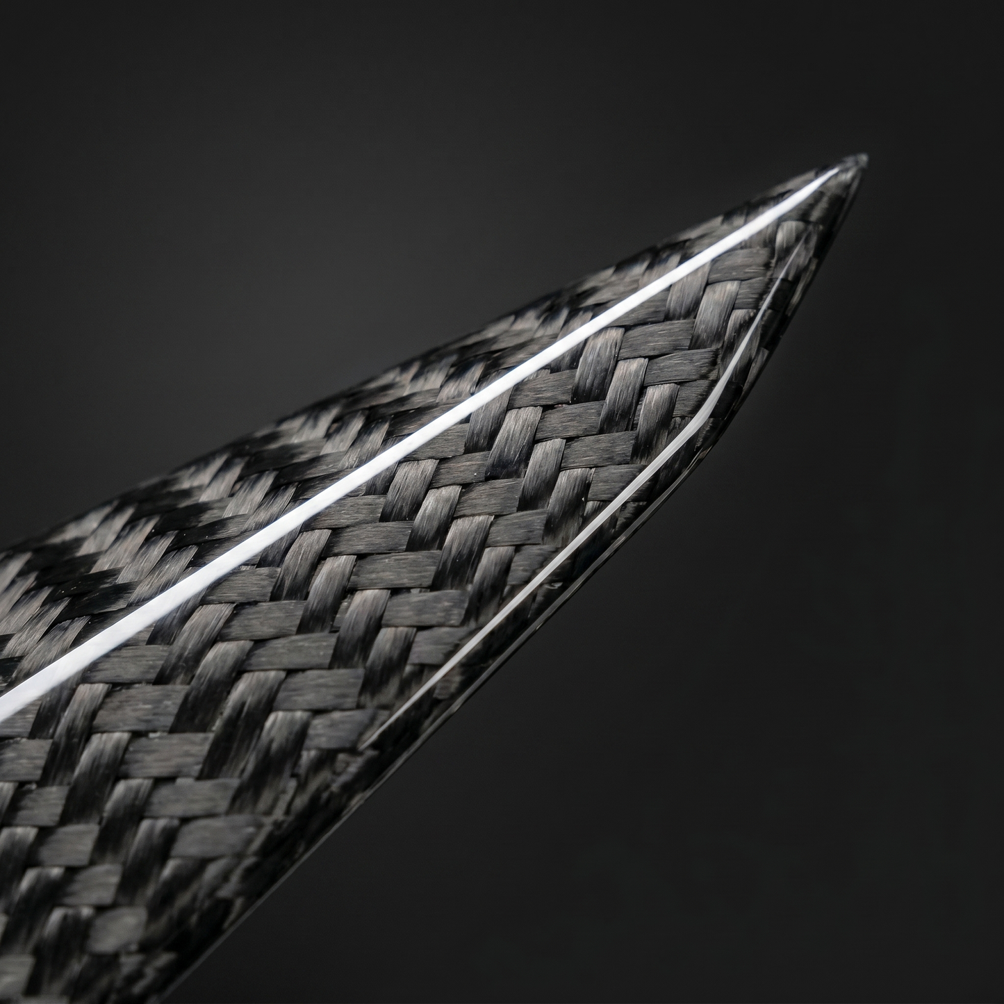 Macro of gloss 2x2 twill carbon weave on BMW G8X front canard flick edge, clean light-bar reflection and machined edge detail