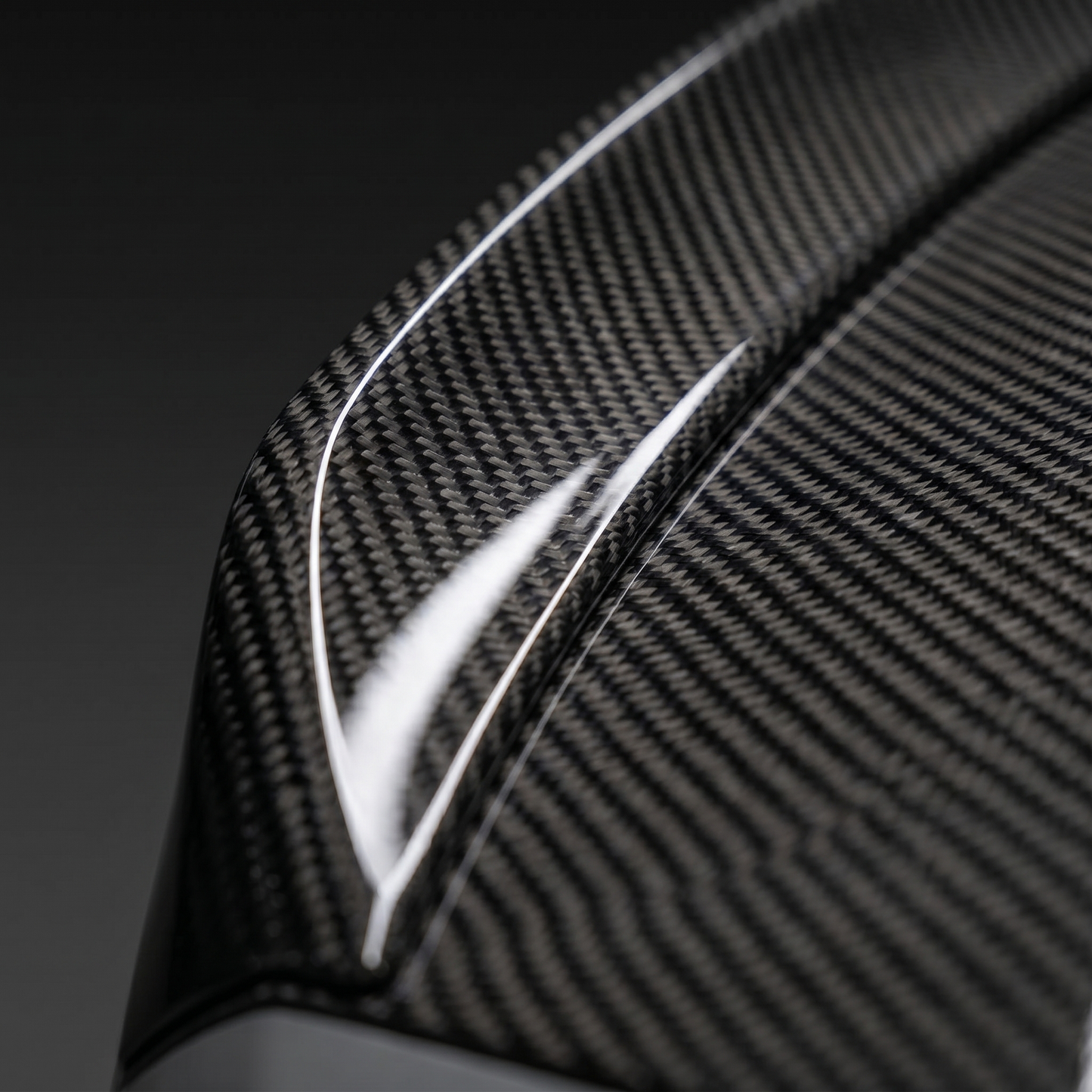 Macro of gloss 2x2 twill carbon weave on BMW G80 M3 CSL ducktail trunk lid edge, clean light-bar reflection and machined edge