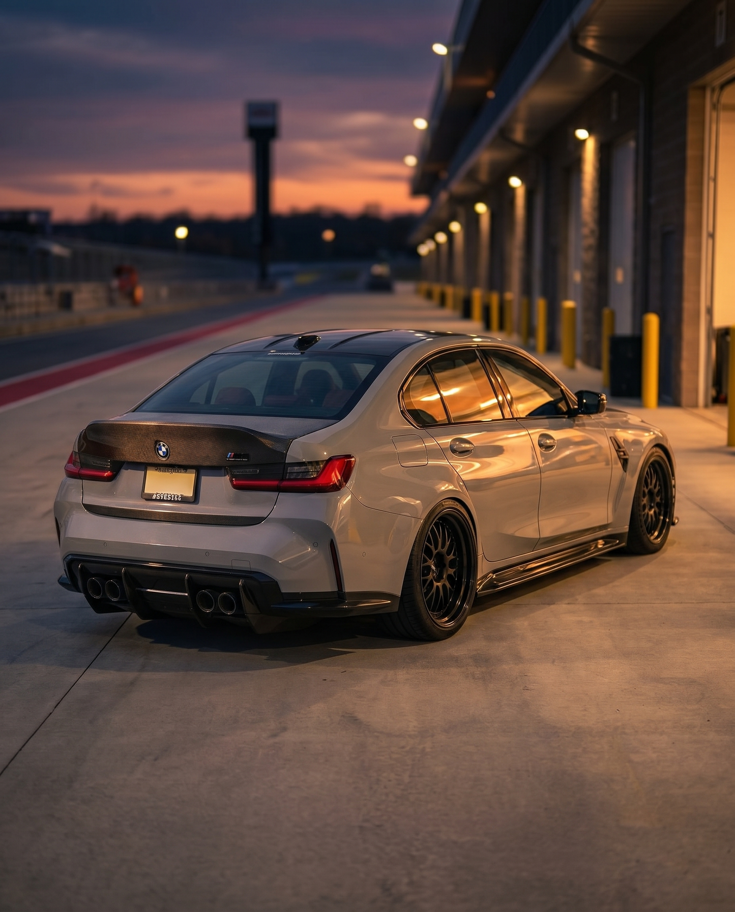 BMW G80 M3 rear 3/4 at dusk with CSL carbon ducktail trunk lid, warm raking light, dramatic race-bred rear silhouette