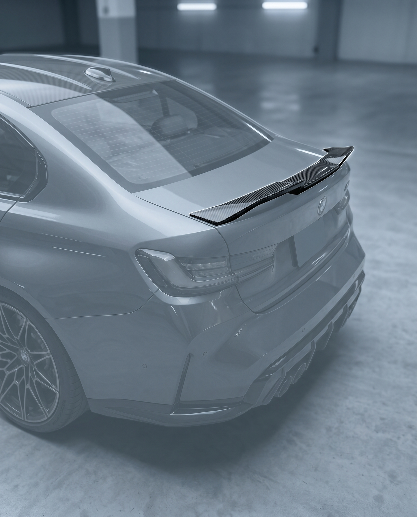 Gloss dry carbon V-style trunk spoiler installed on BMW G80 M3 rear, premium garage lighting highlights clean tape-on fitment