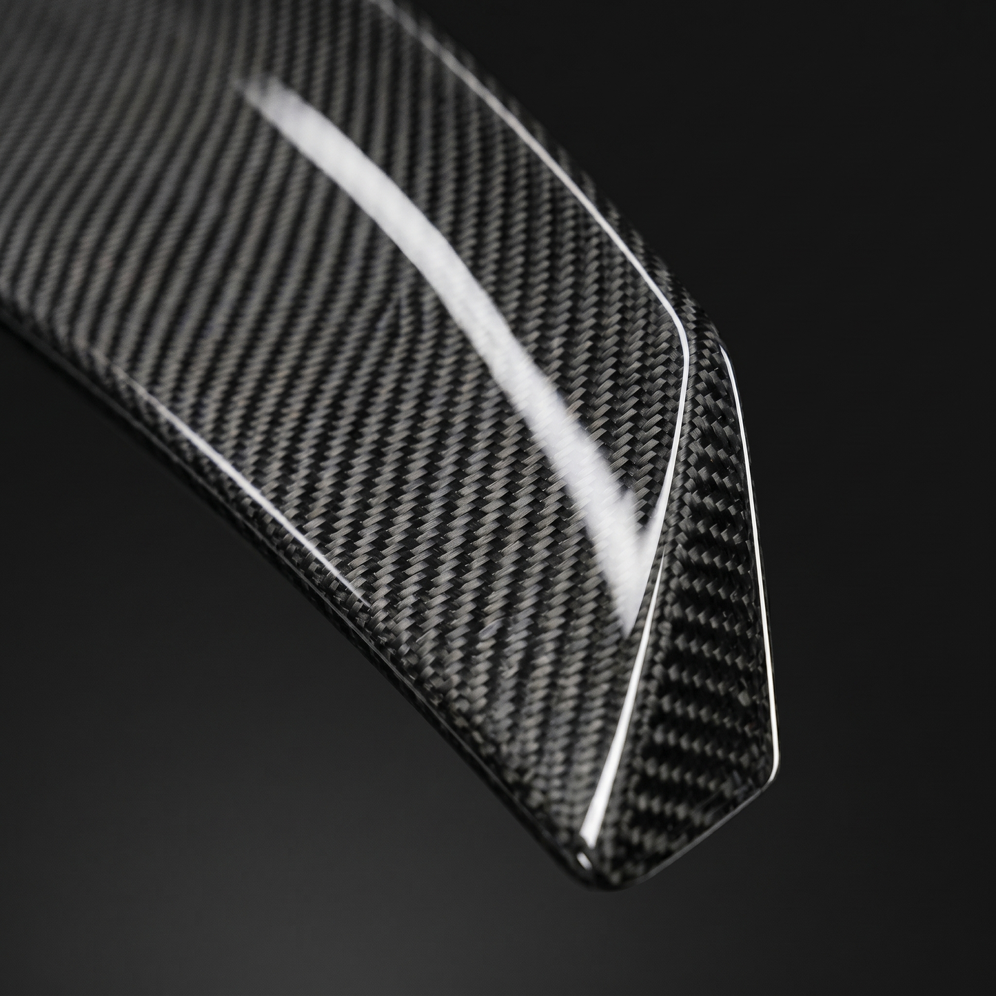 Macro of gloss 2x2 twill weave on PSM-style carbon trunk spoiler for BMW G8X, clear-coat depth and machined edge detail