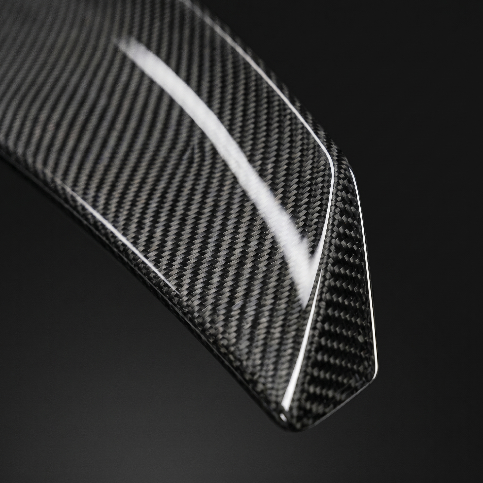 Macro of gloss 2x2 twill weave on PSM-style carbon trunk spoiler for BMW G8X, clear-coat depth and machined edge detail