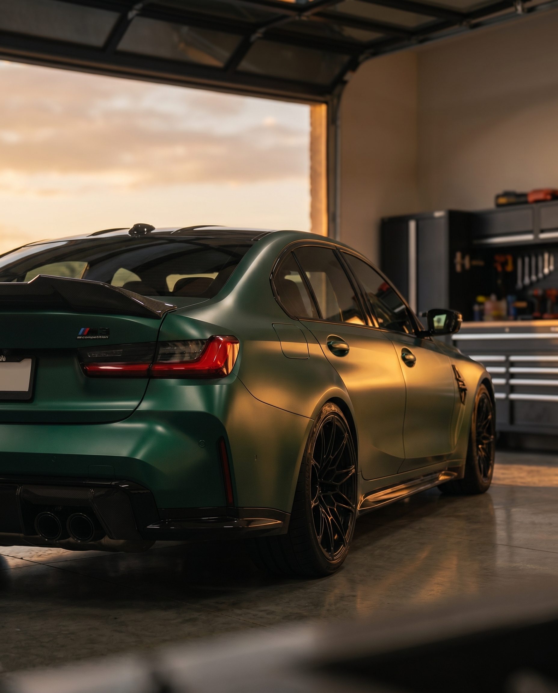 BMW G80 M3 at golden-hour dusk with gloss PSM-style carbon trunk spoiler, rear 3/4 view sharpening the silhouette