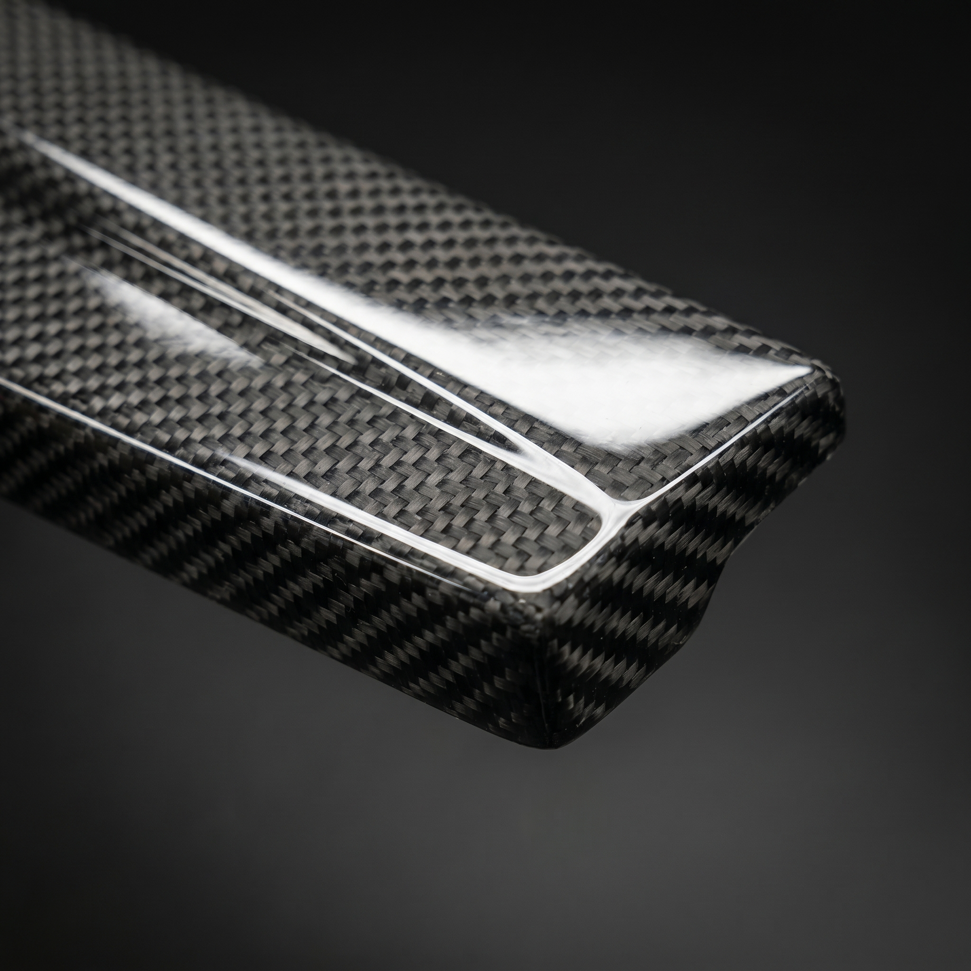 Macro of gloss 2x2 twill weave on carbon side skirt extension for BMW G8X, clear-coat depth and machined edge detail