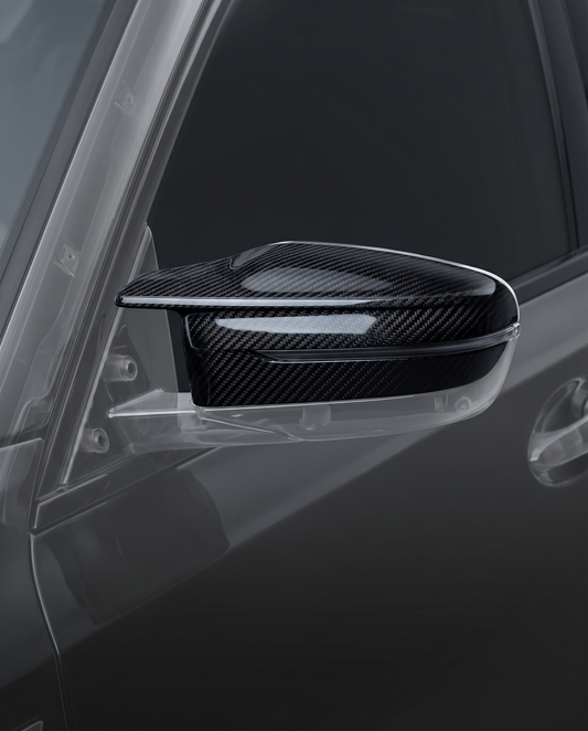 Gloss dry carbon mirror caps for BMW G80 M3, studio hero shot showing curved 2x2 twill weave and machined edge
