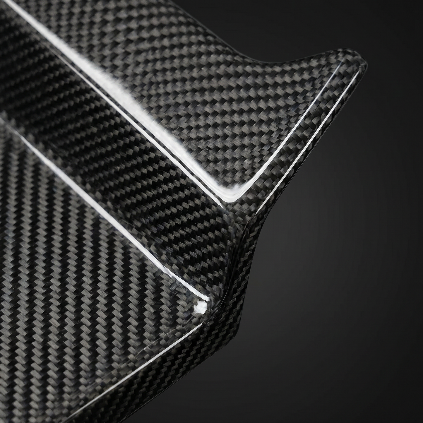 Macro of gloss 2x2 twill weave on MP-style carbon rear diffuser fin for BMW G8X, clear-coat depth and machined edge