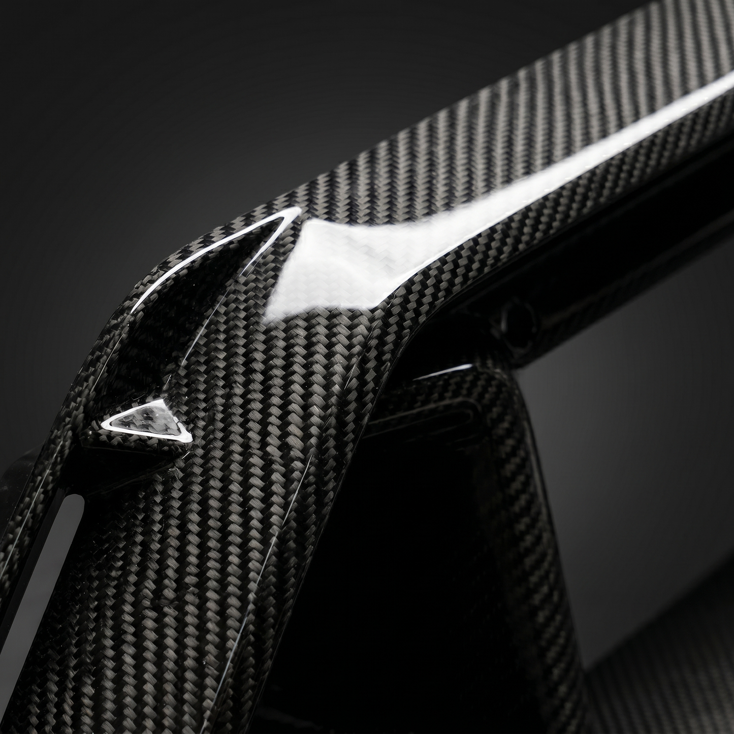 Macro of gloss dry carbon weave on G90 M5 front center vent, clear-coat depth and machined slat edge