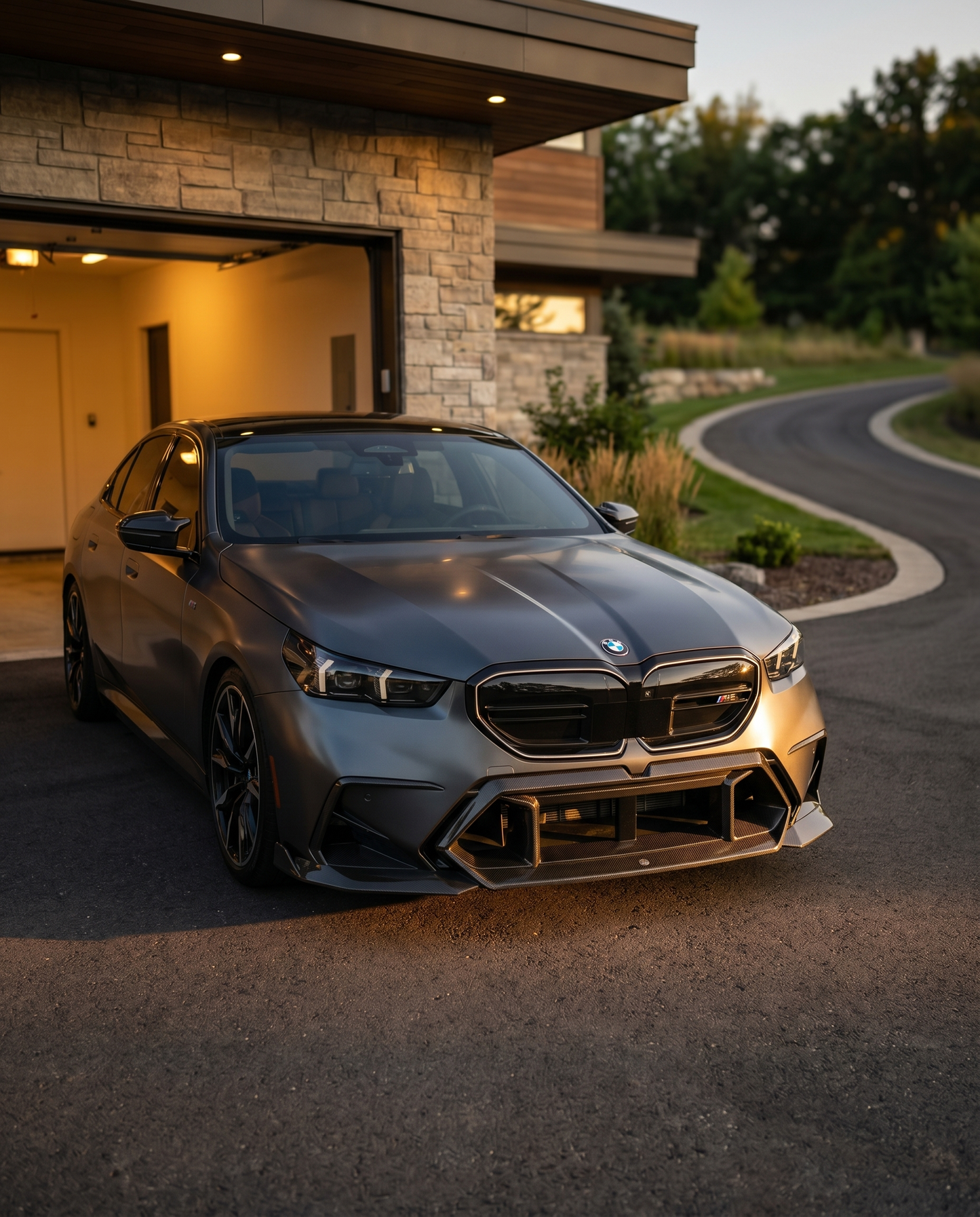 BMW G90 M5 at golden-hour dusk with dry carbon front center vent, front 3/4 view sharpening the front end