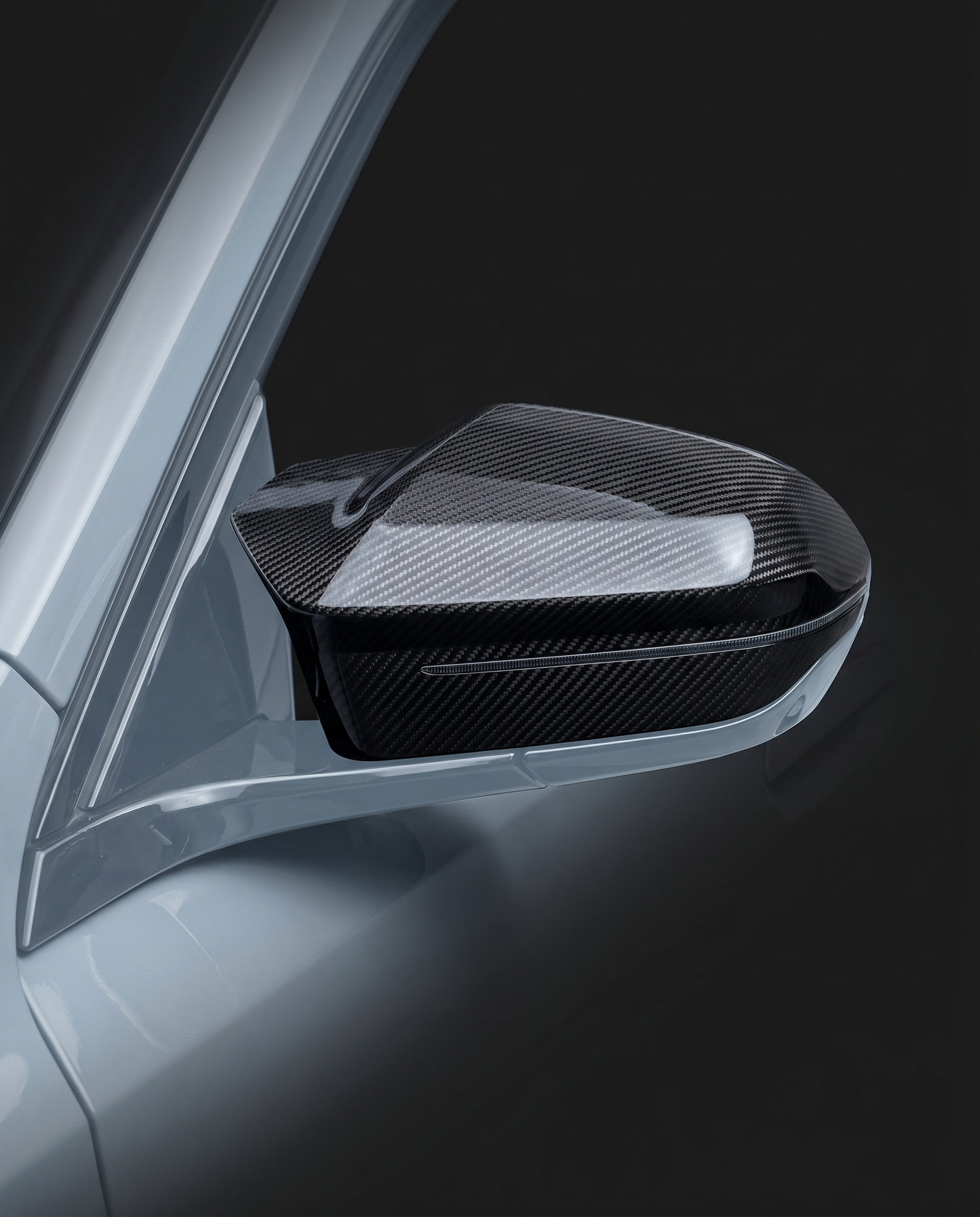 Gloss dry carbon mirror covers for BMW G90 M5, studio hero shot showing curved carbon weave and machined edge