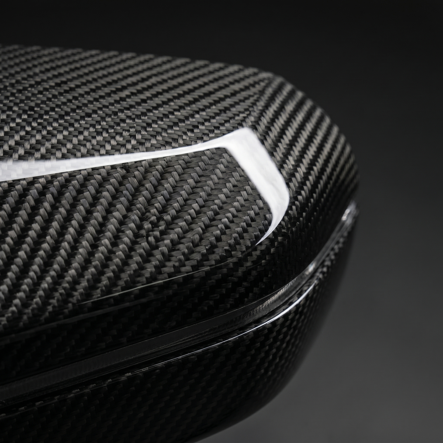 Macro of gloss dry carbon weave on BMW G90 M5 mirror cover, clear-coat depth across the curved surface