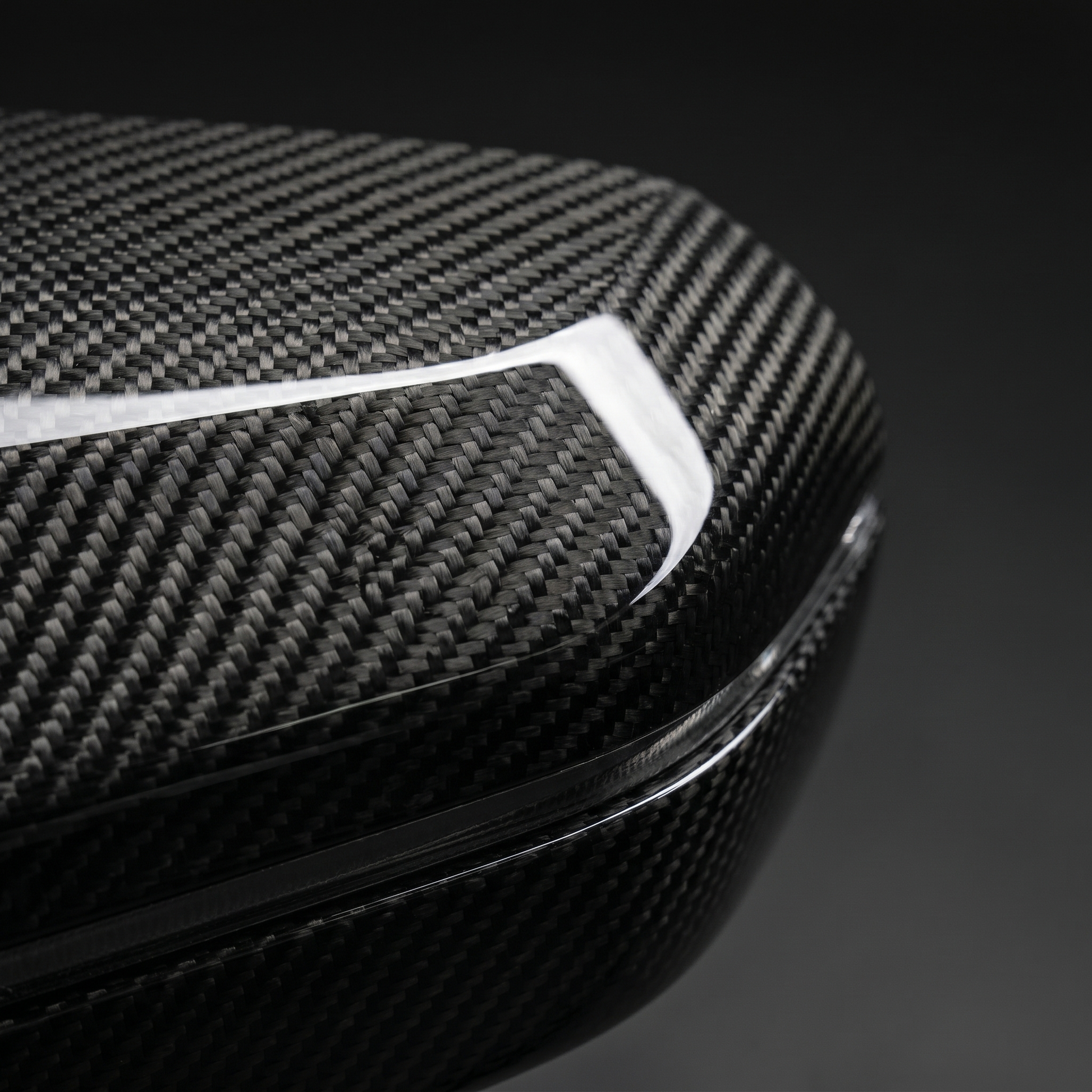Macro of gloss dry carbon weave on BMW G90 M5 mirror cover, clear-coat depth across the curved surface