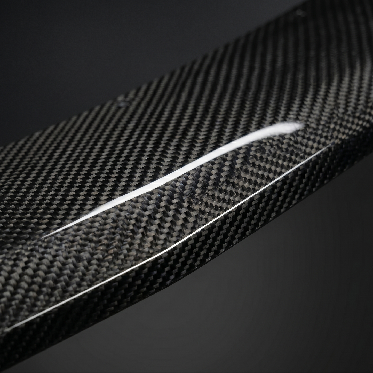 Macro of gloss 2x2 twill dry carbon weave on RZ-style front lip for BMW G90 M5, showing clear-coat depth and machined edge