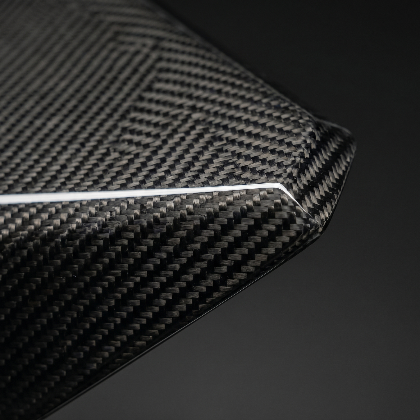 Macro of gloss 2x2 twill dry carbon weave on LAB-style front lip for BMW G90 M5, clear-coat depth and precise machined edge