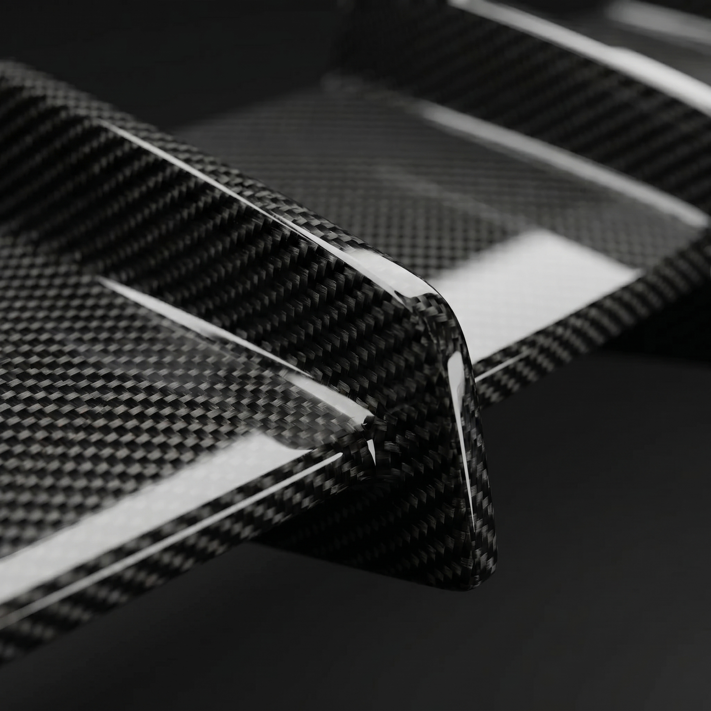 Macro of gloss 2x2 twill dry carbon weave on RZ-style rear diffuser fins for BMW G90 M5, clear-coat depth and crisp edges